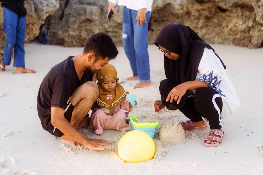 A family is sitting on the beach playing with sand.