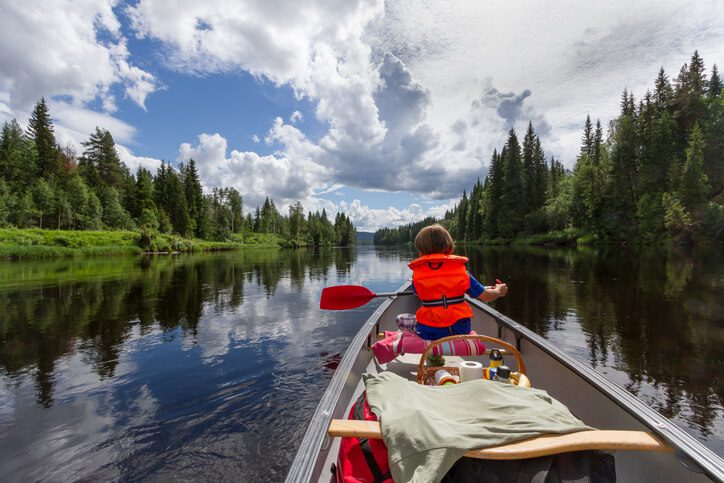 a little boy in the boat wearing the safety jacket