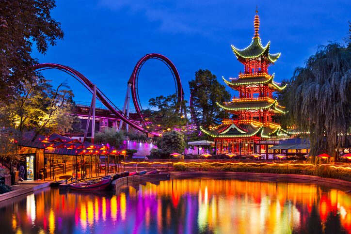A vibrant amusement park at dusk featuringn lights